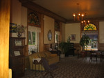  Olive Hotel Lobby, View toward the West with Antique Telephone Switchboard in Corner. Miles City, MT.  It is fun to see all the wonderful well preserved antiques in the Olive Hotel Lobby! It looks like the Original marble tiled floor, front door, and windows. In front door notice the lead mounted curvilinear clear beveled glass designs. This is attributed to 1990's architect Brynju Rivenes. Ditto for window tops with lead mounted Tiffany Styled Colored Glass. Total effect is Pure Victorian! In a Miles City Star article, 29 Nov 88, the Montana State Historical Society is quoted as saying that "The [Olive Hotel] main lobby and entry detail are among the finest in the state". ... "The hotel became a landmark in eastern Montana immediately after its construction and has since served as a social center for area ranchers and travelers." ... "In 1908 when the Chicago, Milwaukee and St. Paul railroad completed its line to the town, a major expansion of the hotel took place in response to the then newly invigorated economy."  ************************************  (Photo = 104-0492...... ZMM Page = NA...... WayPt = 097`|h|' 2358ft)
