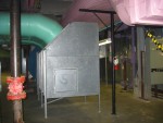 General View of Ventilation System Filter and Conditioning Compartments.  The Two Light Green Pipes Bring Partially Used Air From Various Near Ceiling "Collector Funnels" in the Building into this Grey. This box filters and conditions the air to be re-circulated back to the building (blue ducts) by a large centrifugal blower fan which is the circular blue object in the background. A better view if this blower is seen in the next photo. The pink ducts over head, are for fresh air being brought in from the two Air Intake Horns seen by the Greenhouse at the start of this album.  HVAC Equipment Room, Basement of Science Building, USCA Campus, Aiken, SC.  ************************************  (Photo = 5141 ...... WayPt = `000 |w|' 420 ft)
